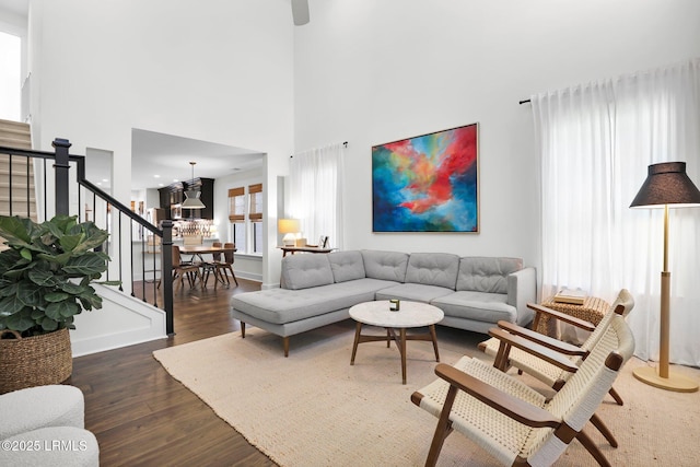 living room with baseboards, stairway, a chandelier, and wood finished floors