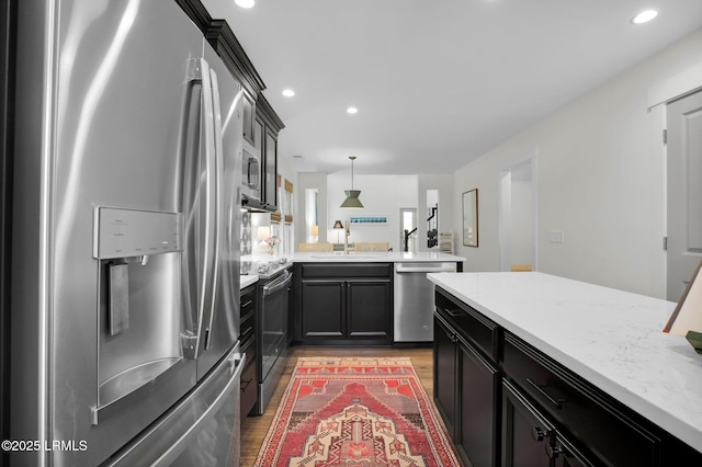 kitchen with recessed lighting, a sink, light wood finished floors, a peninsula, and appliances with stainless steel finishes
