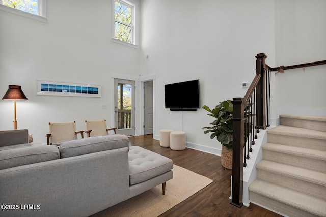 living room featuring dark wood-type flooring, stairs, baseboards, and a healthy amount of sunlight
