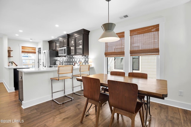 dining space with dark wood-style flooring, baseboards, and visible vents