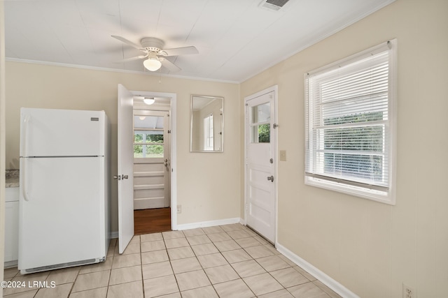 doorway featuring crown molding, a healthy amount of sunlight, light tile patterned floors, and ceiling fan