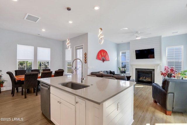 kitchen featuring visible vents, open floor plan, a sink, a fireplace, and stainless steel dishwasher