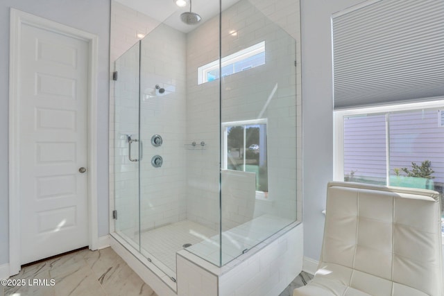 bathroom with marble finish floor, a shower stall, and baseboards