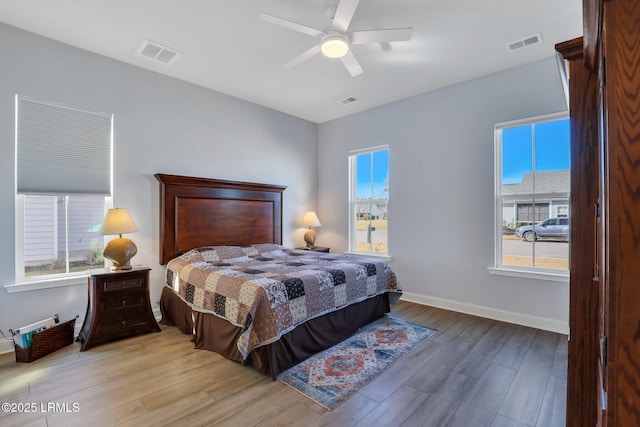 bedroom featuring a ceiling fan, baseboards, visible vents, and wood finished floors