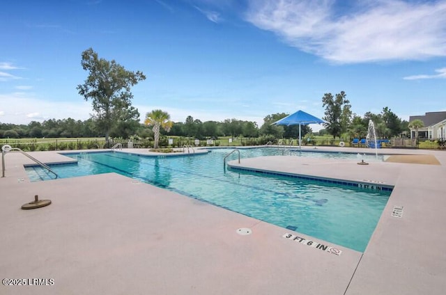 pool with a patio area and fence