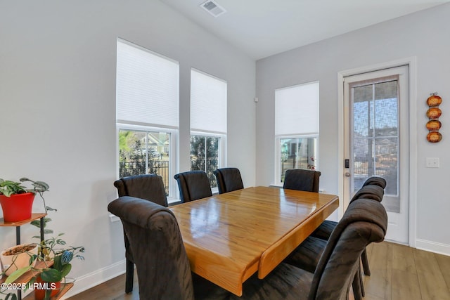 dining area with wood finished floors, visible vents, and baseboards