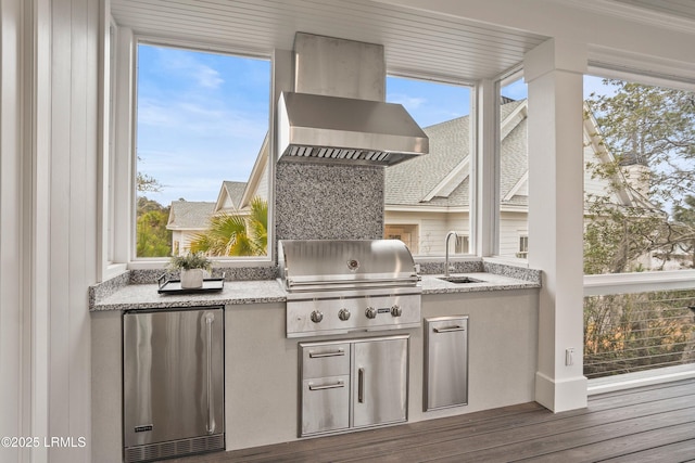 exterior space featuring island exhaust hood, sink, light stone counters, and refrigerator