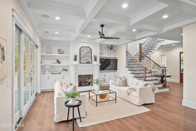 living room featuring coffered ceiling, beam ceiling, light hardwood / wood-style floors, and crown molding