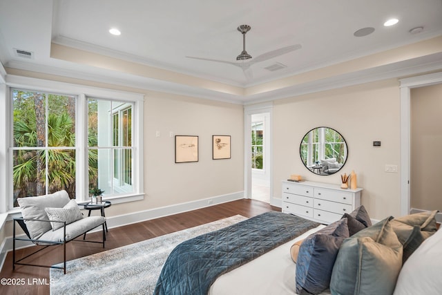 bedroom with dark wood-type flooring, ornamental molding, and a raised ceiling