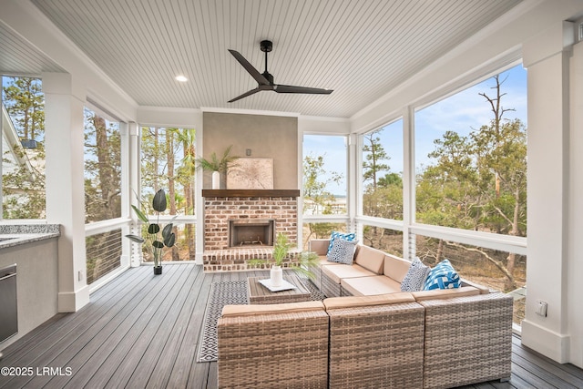 sunroom with an outdoor brick fireplace, wooden ceiling, and ceiling fan