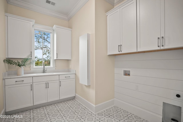 clothes washing area with sink, crown molding, hookup for a washing machine, and cabinets