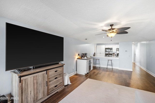 living room featuring ceiling fan, dark hardwood / wood-style floors, and a textured ceiling