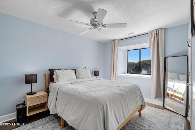 bedroom with dark wood-type flooring, a textured ceiling, and ceiling fan