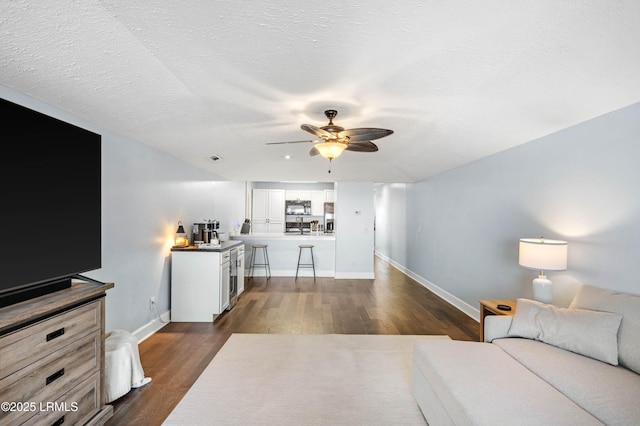 living room with ceiling fan, dark hardwood / wood-style floors, and a textured ceiling