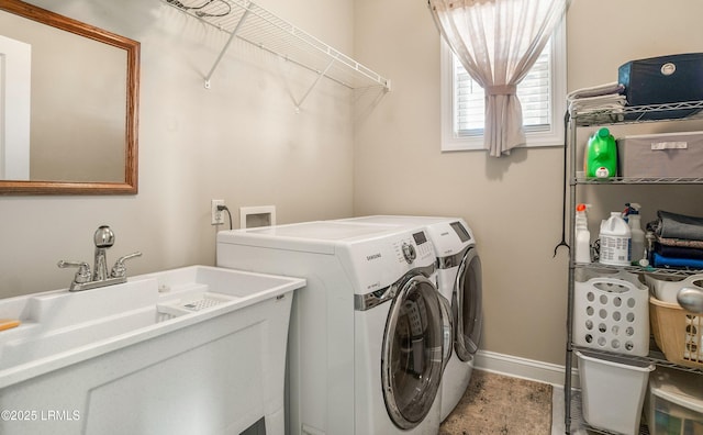 clothes washing area with a sink, washer and clothes dryer, baseboards, and laundry area