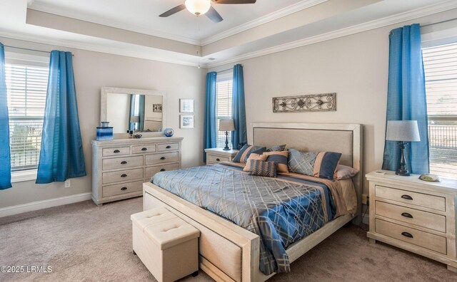 bedroom with a tray ceiling, multiple windows, crown molding, and light colored carpet