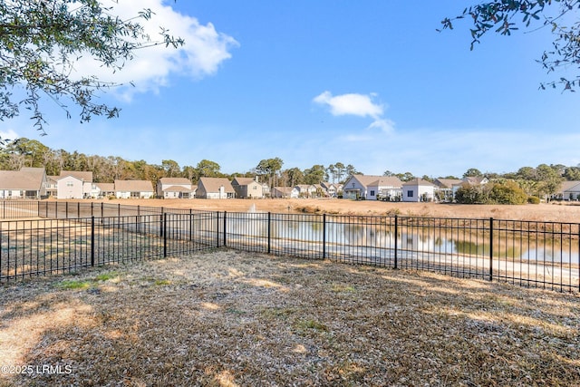 view of yard featuring a residential view, a water view, and fence