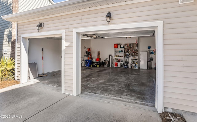 garage featuring freestanding refrigerator and concrete driveway