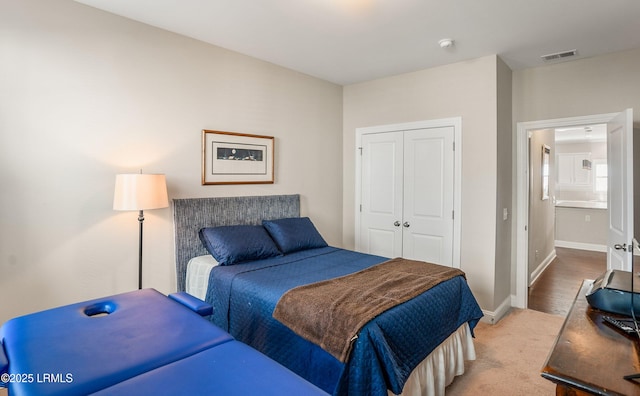 bedroom with baseboards, a closet, light colored carpet, and visible vents