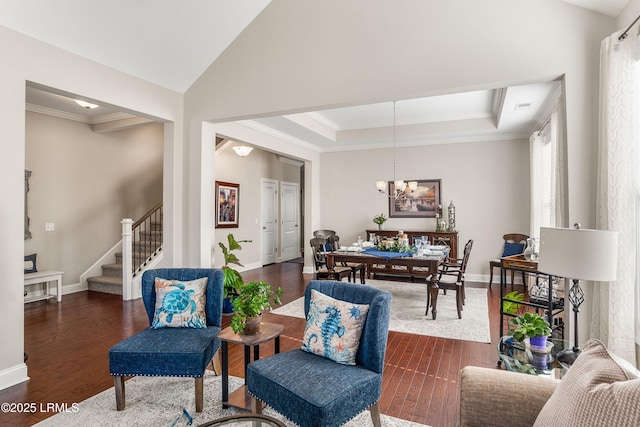 living room with dark wood-style flooring, an inviting chandelier, stairway, and a raised ceiling
