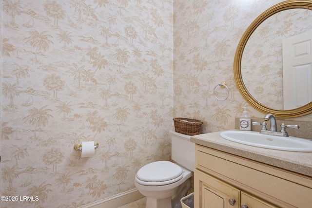 bathroom with toilet, wallpapered walls, and vanity