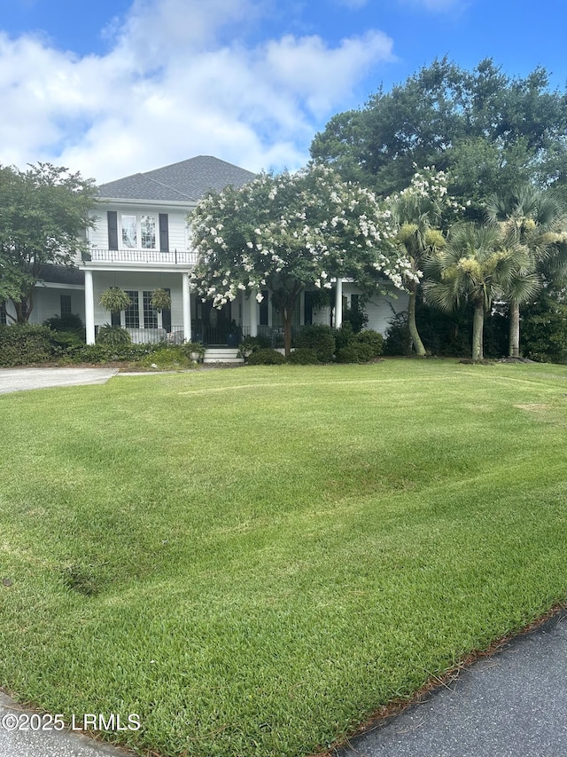 view of front facade with a balcony and a front lawn