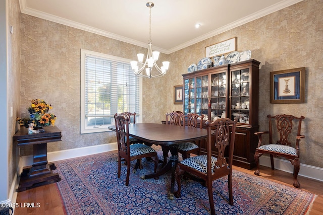 dining room with an inviting chandelier, crown molding, baseboards, and wood finished floors