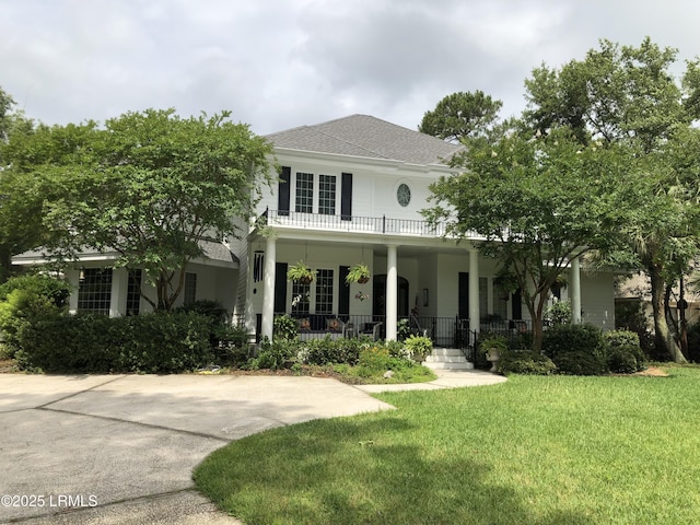 view of front of home with a porch, roof with shingles, a front yard, and a balcony