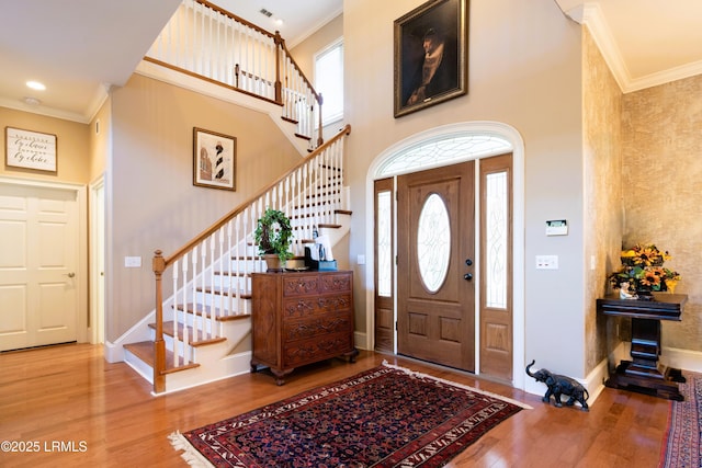 foyer entrance with plenty of natural light, ornamental molding, and wood finished floors