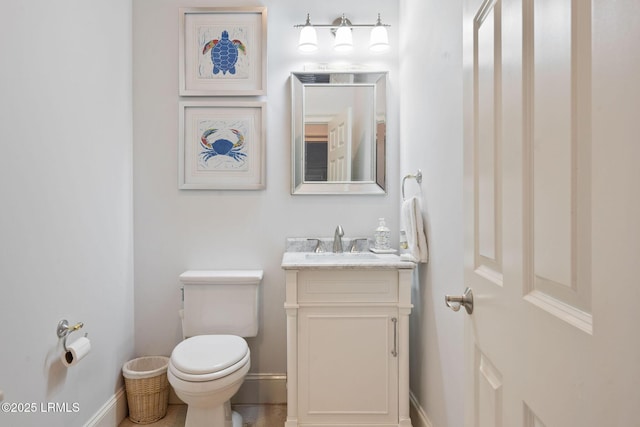 half bath featuring toilet, baseboards, and vanity