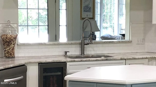 kitchen with tasteful backsplash, wine cooler, a sink, and a healthy amount of sunlight