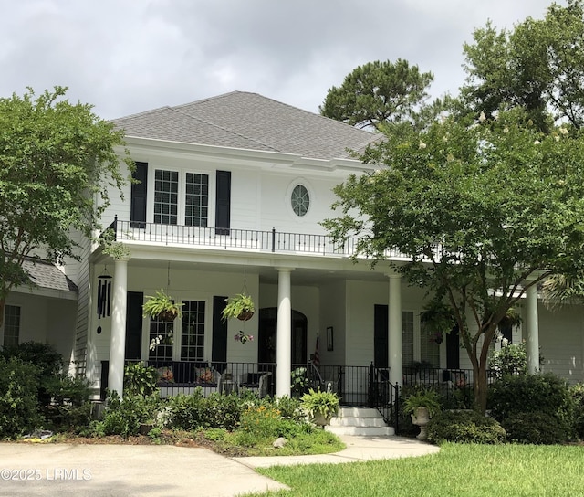 view of front facade featuring a porch, a shingled roof, and a balcony