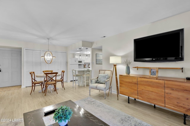 living room featuring a chandelier and light wood-type flooring