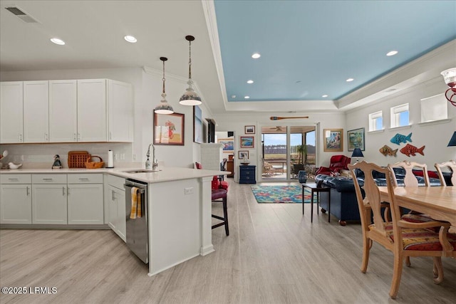 kitchen with decorative light fixtures, white cabinetry, sink, stainless steel dishwasher, and a raised ceiling