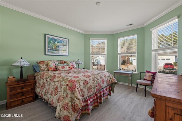 bedroom with ornamental molding and light hardwood / wood-style floors