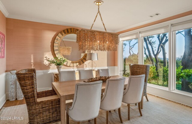 dining space with ornamental molding, wood-type flooring, and a notable chandelier