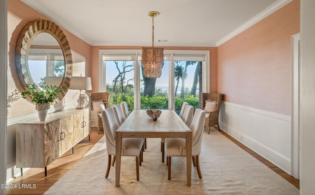 dining area with ornamental molding, light hardwood / wood-style floors, and a notable chandelier