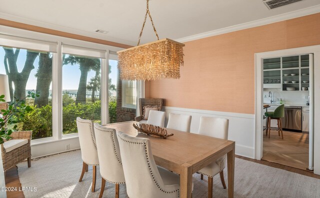 dining space featuring ornamental molding, sink, parquet floors, and a notable chandelier