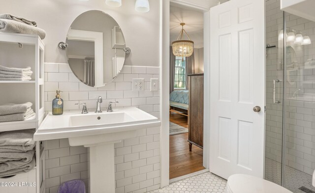 bathroom with toilet, an enclosed shower, tile patterned flooring, and tile walls