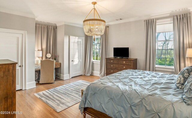 bedroom featuring light hardwood / wood-style flooring, ornamental molding, and a chandelier