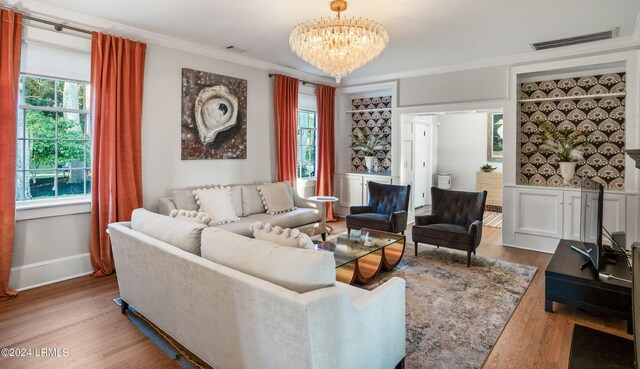 living room featuring a notable chandelier, hardwood / wood-style flooring, and ornamental molding