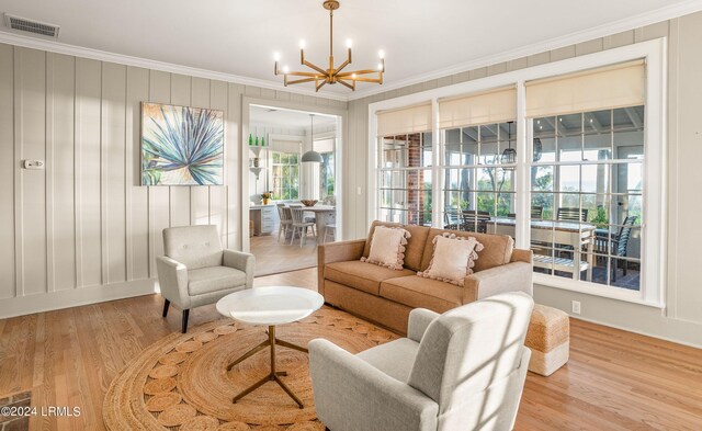 living room featuring crown molding, an inviting chandelier, and light wood-type flooring