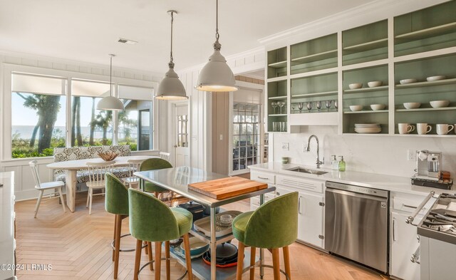 kitchen with decorative light fixtures, dishwasher, sink, white cabinets, and light parquet floors