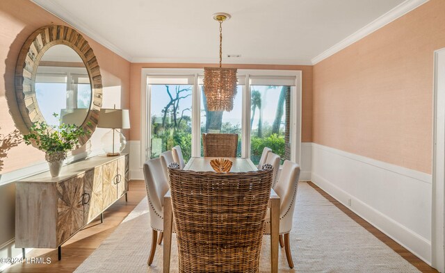 dining space with hardwood / wood-style floors, ornamental molding, and a chandelier