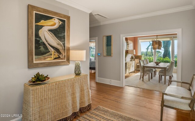 hall with crown molding, an inviting chandelier, and hardwood / wood-style floors