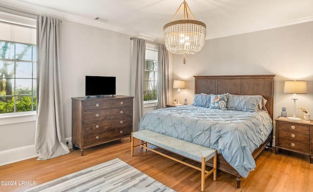 bedroom with ornamental molding, a chandelier, and light hardwood / wood-style floors