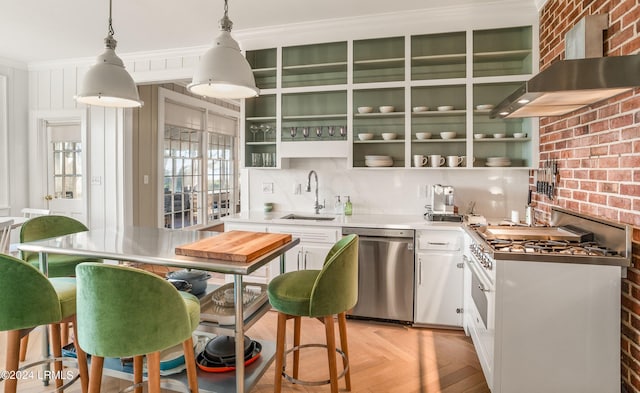 kitchen featuring wall chimney exhaust hood, stainless steel appliances, sink, light parquet flooring, and white cabinets