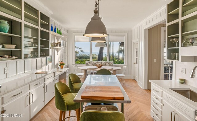 dining area featuring sink, crown molding, and light parquet floors