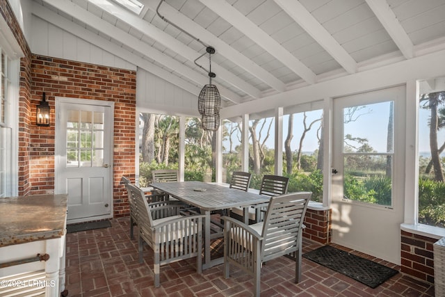 sunroom with vaulted ceiling with beams and a healthy amount of sunlight