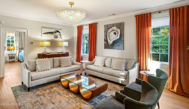 living room featuring wood-type flooring, plenty of natural light, ornamental molding, and an inviting chandelier